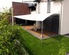 Viereckiges weisses Sonnensegel befestigt an 2 Aufhängepunkten am Haus sowie 2 Segelmasten von Lisori über der Gartenterasse eines Einfamilienhauses | Lisori Sonnensegel