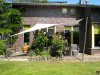 Viereckiges beiges Sonnensegel befestigt an 2 Aufhängepunkten an Holzfassade sowie 2 Segelmasten von Lisori über der Gartenterasse eines Einfamilienhauses | Lisori Sonnensegel