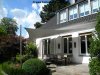 Fünfeckiges graues Sonnensegel befestigt an 3 Aufhängepunkten an der Hausfassade sowie 2 Edelstahl-Segelmasten von Lisori über der Terrasse eines Einfamilienhauses | Lisori Sonnensegel