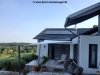 Ein Sonnensegel von Lisori spendet Schatten auf der Terrasse eines Hauses mit Solarpanel auf dem Dach. Ein entspannter und umweltfreundlicher Ort!
