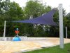 Ein großes blaues dreieckiges Sonnensegel beschattet freistehend mit drei Segelmasten einen Wasserspielbereich in einem Freibad | Lisori Sonnensegel