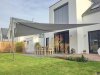 Graues, großes aufrollbares Sonnensegel mit 2 Edelstahl-Segelmasten und 2 Aufhängepunkten an der Hausfassade über über Garten und Terrasse des modernen Einfamilienhauses | Lisori Sonnensegel