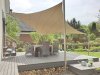 Dreieckiges beiges Sonnensegel befestigt an 1 Aufhängepunkten an der Hausfassade sowie 3 Segelmasten von Lisori über der Holzterrasse eines Einfamilienhauses | Lisori Sonnensegel