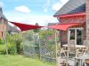 Fünfeckiges rotes Sonnensegel befestigt an 2 Aufhängepunkten an der Hausfassade sowie 3 Edelstahl-Segelmasten von Lisori über der Terrasse eines Einfamilienhauses | Lisori Sonnensegel