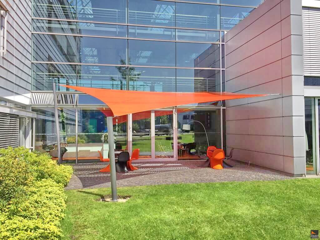 Ein großes oranges Sonnensegel in Viereckform beschattet eine bestuhlte Terasse der Außenfläche einer Firma | Lisori Sonnensegel